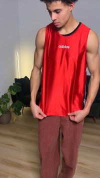 Rød ermeløs atletisk tanktopp med glatt tekstur, med adidas-logo, kombinert med brune rutete bukser med vide ben.