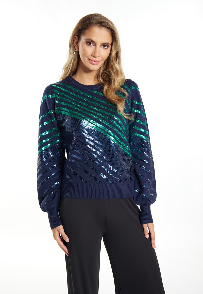 Marineblaues Sweatshirt mit diagonalen Streifen aus grünen und blauen Pailletten, geripptem Kragen und Bündchen sowie puffigen Ärmeln. Glatte Textur.