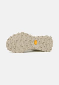 Vibram outsole with a rugged tread pattern in light beige. Features textured grips designed for traction on varied surfaces.