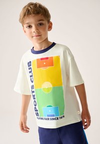 Balti trumpomis rankovėmis marškinėliai su spalvinga futbolo aikštelės išdėstymo grafika oranžinės, geltonos, žalios ir mėlynos spalvų su tamsiai mėlynomis detalėmis.