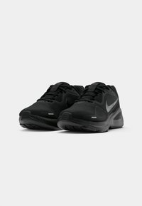 Une paire de baskets de sport noires avec des lacets et des logos Nike visibles, placées côte à côte sur un fond blanc.