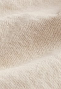 Béžová tkaná látka s texturovaným povrchem, obsahující jemný vzor a měkký, hladký vzhled.