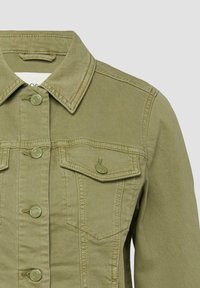 Zbliżenie na przednią część oliwkowo-zielonej kurtki dżinsowej z kołnierzem, zatrzaskiwaną patką kieszeni i widocznymi szczegółami szwów.