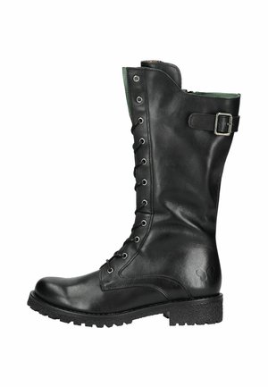 Botte en cuir noir montant jusqu'au genou avec un laçage sur le devant, doublure verte, détail de boucle et semelle en caoutchouc texturé pour une meilleure adhérence. Logo circulaire sur le côté.