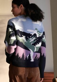 Strikket sweater med et bjerglandskabsdesign i nuancer af blå, grøn, lilla og sort. Ribbet manchetter og kant.
