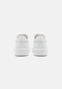 Hvite skinnsekker med flat gummisåle, avrundet tå og minimalistisk design. Har stålte detaljer og en pull-tab ved hælen.