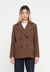 Brun dobbeltspent ullblandingsfrakk med store svarte knapper, klassisk revers og sidelommer, med en strukturert form og teksturert stoff.