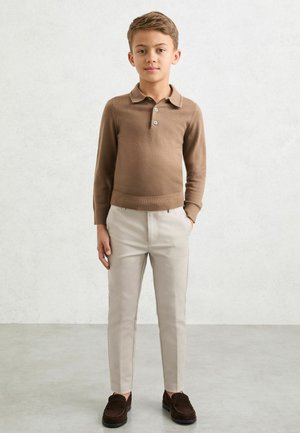 Brązowa koszulka polo z długim rękawem i zapinanym na trzy guziki dekoltem, połączona z jasno beżowymi spodnie na miarę oraz ciemnobrązowymi mokasynami. Gładka faktura, dopasowany krój.