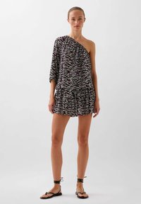 Rochie cu o singură umăr, de culoare neagră, cu un model ondulat în nuanțe de roz și alb, având o margine ondulată și un material ușor. Sandale la gleznă ajustabile.
