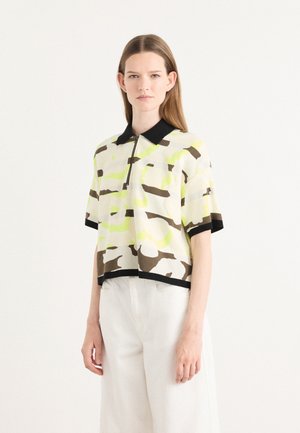 Korte mouw polo shirt in een lichte stof, met een camouflagedessin in geel, bruin en wit, voorzien van een zwarte kraag en een rits.
