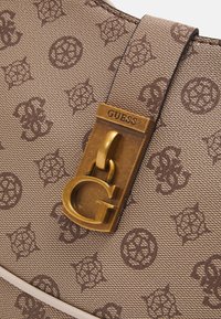 Hnědá syntetická kabelka s embosovaným vzorem loga, zlatými prvky a výrazným uzávěrem ve tvaru loga G. Hladká textura a strukturovaný design.