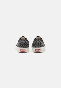 Sorte og grå rutete slip-on sneakers med hvite gummisåler og røde logo detaljer på hælen. Holdbar tekstiloverdel med syddetaljer.