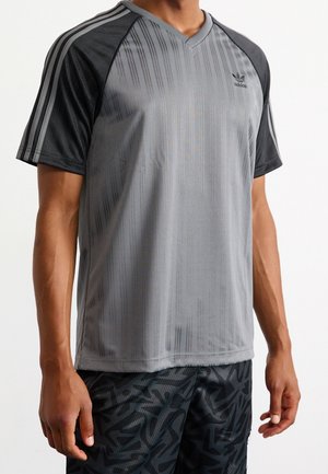 Grijze sportshirt met V-hals, voorzien van subtiele verticale strepen en zwarte panelen op de schouders. Adidas-logo op de borst.