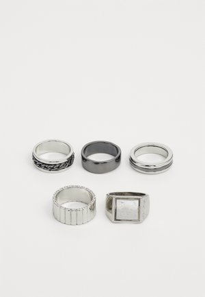 Päť prsteňov vystavených: dva strieborné prstene, jeden čierny prsten, jeden strieborný s vzorovaným okrajom a jeden s hranatým strieborným detailom.