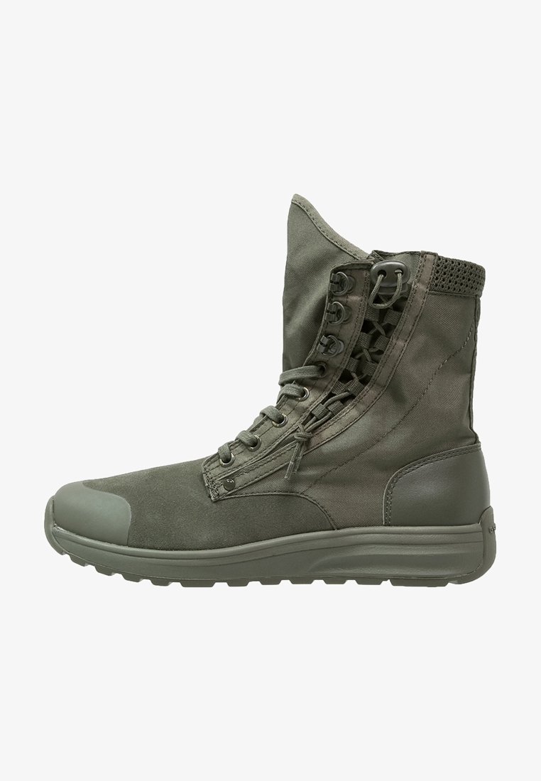 Botte militaire montante de couleur vert olive avec fermeture éclair latérale, laçage devant, col de cheville rembourré et semelle en caoutchouc texturée.