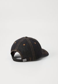 Casquette de baseball en denim foncé avec des coutures orange, bandeau ajustable à l'arrière, couronne ronde et visière incurvée. Design simple sans logos.