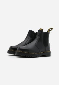 Stivali Chelsea in pelle nera con pannelli elasticizzati laterali, cuciture gialle e suola in gomma robusta. Presentano una linguetta per una facile calzata.