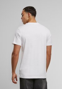 Witte katoenen T-shirt met korte mouwen, een ronde hals en een gladde textuur. De achterkant heeft een eenvoudig ontwerp zonder grafische elementen.