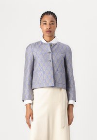 Blå cropped jakke med gullskallmønster, sølvknapper og hvit krage. Glatt tekstur, skreddersydd design og lange ermer.