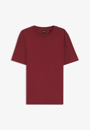 T-shirt uni bordeaux à manches courtes et col rond avec un tissu subtilement texturé et une petite étiquette noire à l'intérieur du col.