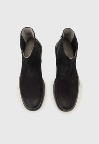 Stivaletti neri in pelle con una finitura liscia, pannelli laterali elastici e dettagli testurizzati sul gambale. Design elegante con punta arrotondata.