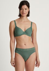 Groene lingerie set met een gevoerde bh met kantafwerking en bijpassende slip. Het materiaal lijkt glad met een naadloos ontwerp en delicate accenten.