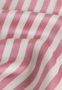 Tela suave con rayas verticales alternadas en rosa suave y blanco, ligeramente doblada para mostrar textura y brillo.