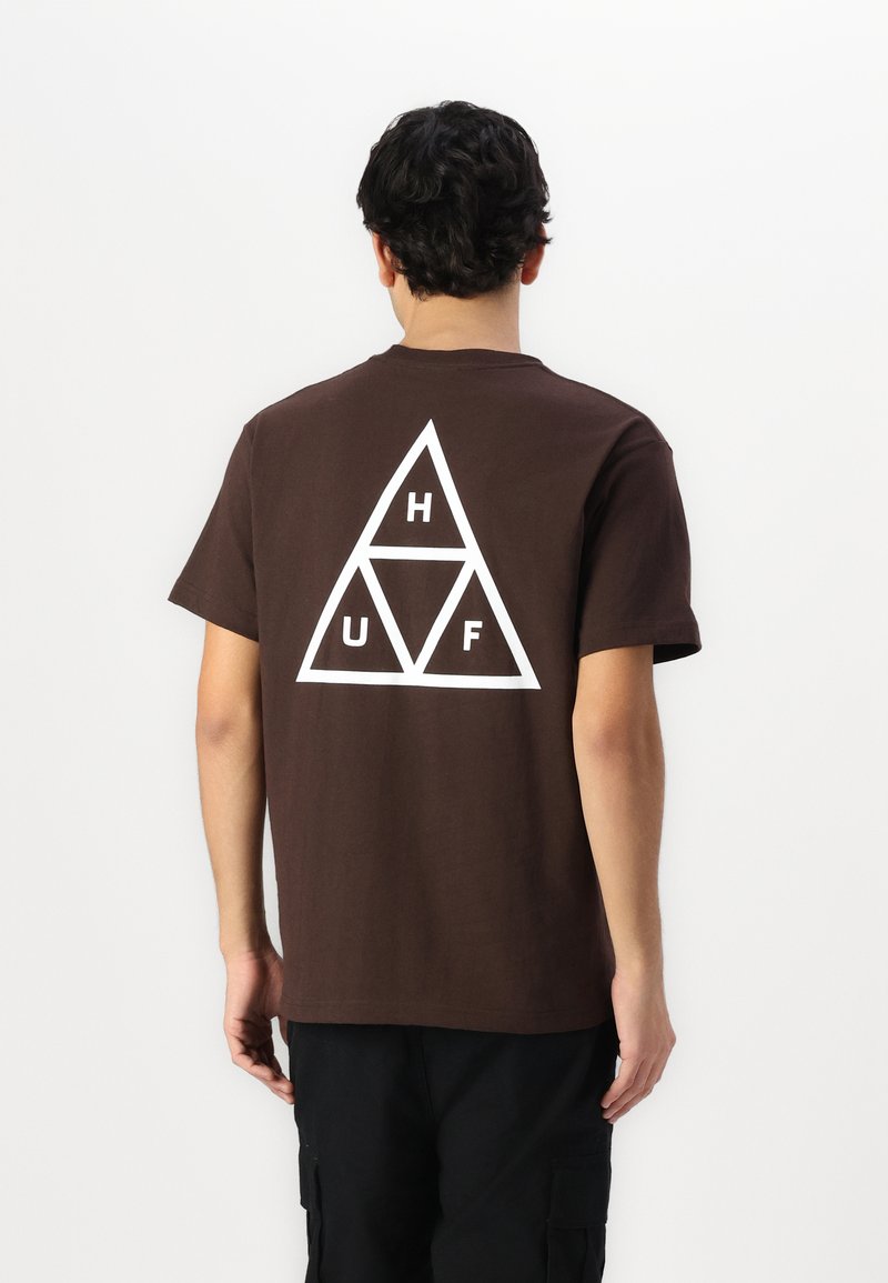 Camiseta de algodón marrón con mangas cortas. Logotipo triangular blanco con las letras "H", "U" y "F" en la parte posterior. Textura suave, ajuste estándar.