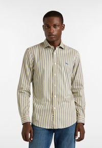 Raitapaita, jossa on keltainen, sininen ja valkoinen väri, slim fit -leikkaus, pitkät hihat ja pieni sininen logo rinnassa.