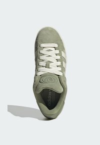 Zelené semišové tenisky s bielym šnurovaním, tromi bielymi pruhmi na boku a okrúhlym logom na jazyku. Plochá gumová podrážka.