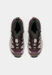 Μωβ και γκρι παπούτσια πεζοπορίας με υφή στο πάνω μέρος, ενισχυμένη ακροδάχτυλη προστασία και μαύρα κορδόνια. Διαθέτουν μαξιλαρωμένο, υποστηρικτικό εσωτερικό.