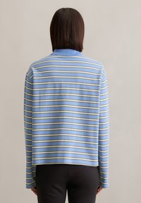 Pull léger bleu avec des rayures verticales en jaune pâle et blanc. Comprend un col, des manches longues et une coupe décontractée. Texture de tissu douce.