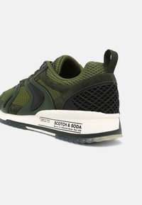 Sneaker in mesh e suede verde e nero con suola bianca, anello sul tallone, retro testurizzato e branding "Scotch & Soda" sulla parte laterale della suola.