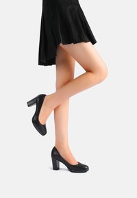 Scarpe nere in pelle con tacco alto, punta rotonda e tacco a blocco spesso. Texture liscia, design semplice e senza decorazioni visibili.