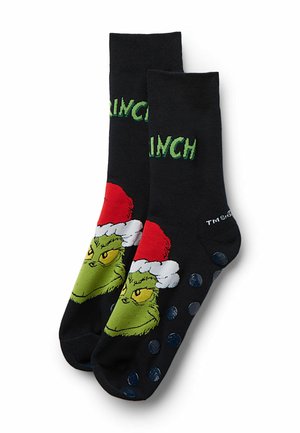 Zwarte sokken met een groene Grinch-figuur die een rode kerstmanmuts draagt. De tekst luidt "GRINCH." Gelaagde blauwe stippen op de zool voor grip.