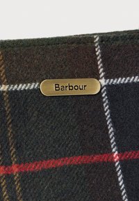 Bruine en groene geruite wollen stof met een bronzen label waarin "Barbour" is geperst. Bevat witte en rode accentlijnen. Zachte textuur.