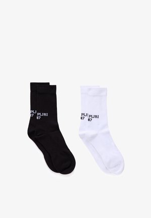 Ein Paar schwarze Socken und ein Paar weiße Socken, jeweils mit gerippten Bündchen und dem Schriftzug "PLJRI 87" nahe dem oberen Rand.