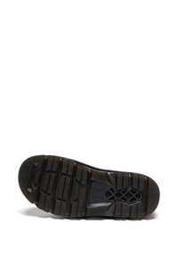Semelle d'une botte noire avec des crampons profonds, une prise texturée et un motif croix et losange près de la voûte plantaire, sur fond blanc.