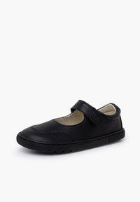 Chaussure noire style Mary Jane avec bride velcro et semelle en caoutchouc texturée, conçue pour enfants, présentée sur fond blanc.