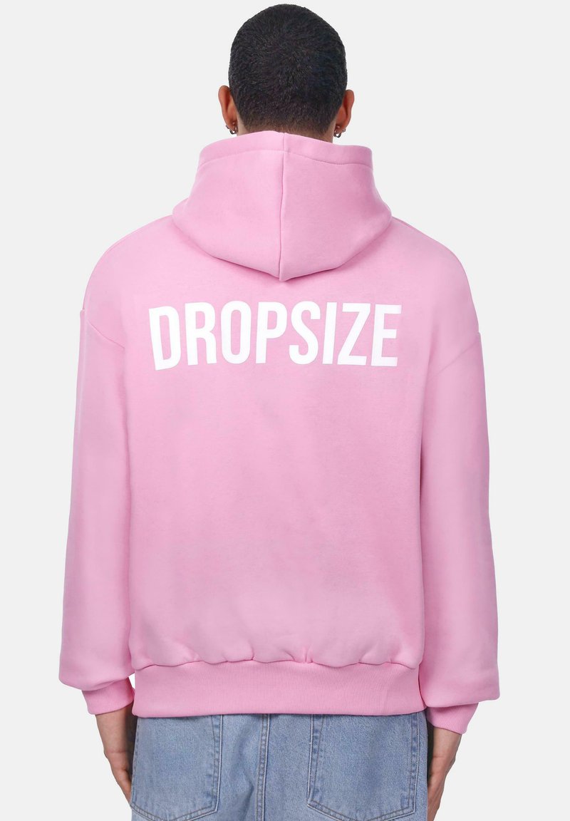 Felpa rosa con testo bianco "DROPSIZE" sulla schiena, dotata di cappuccio con cordino, polsini a costine e vestibilità rilassata. Tessuto morbido e colore uniforme.