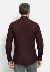 Burgunderfarbene Button-Down-Bluse mit strukturiertem Muster, langen Ärmeln und schwarzen Knöpfen. Figurschnitt mit Spitzekragen und genähten Nähten.