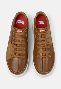 Braune Freizeitschuhe mit Leder- und Wildledereinsätzen, ausgestattet mit Schnürsenkeln und roten Innensohlen, die mit "CAMPER" und "TWINS" beschriftet sind.
