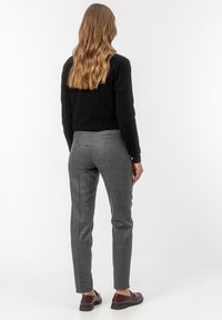 Slim-fit szare spodnie w kratę z teksturowanej tkaniny, z tylnymi kieszeniami. W zestawieniu z brązowymi lordami, pokazane od tyłu na jednolitym tle.