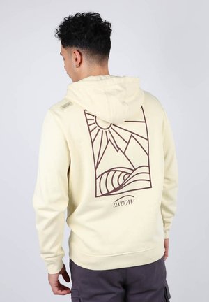Sweatshirt à capuche crème avec un graphique en contour marron représentant des montagnes et des vagues au dos, et un logo en bas au centre.