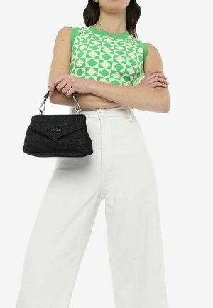 Mini borsa nera texturizzata con manico a catena, dotata di una semplice chiusura a pattina. La borsa è tenuta contro un modello che indossa una maglietta geometrica verde e bianca.