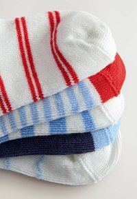 Cuatro pares de calcetines apilados: blancos con rayas rojas, blancos con rayas azules y un par azul marino. Material de algodón con textura acanalada.