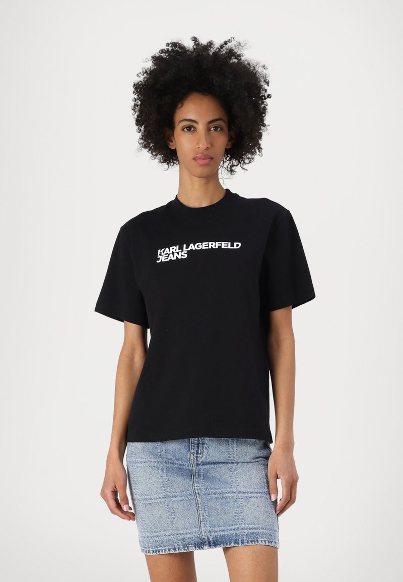 Fekete pamut póló, amelyen fehér "KARL LAGERFELD JEANS" logó található elöl, világoskék farmer szoknyával párosítva. Kényelmes szabás.