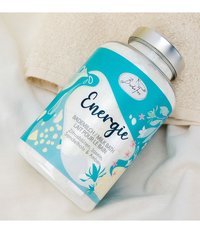 Bottle of Badetee Energie milk bath with lemon blossoms, jasmine, sandalwood, and amber on beige fabric background.