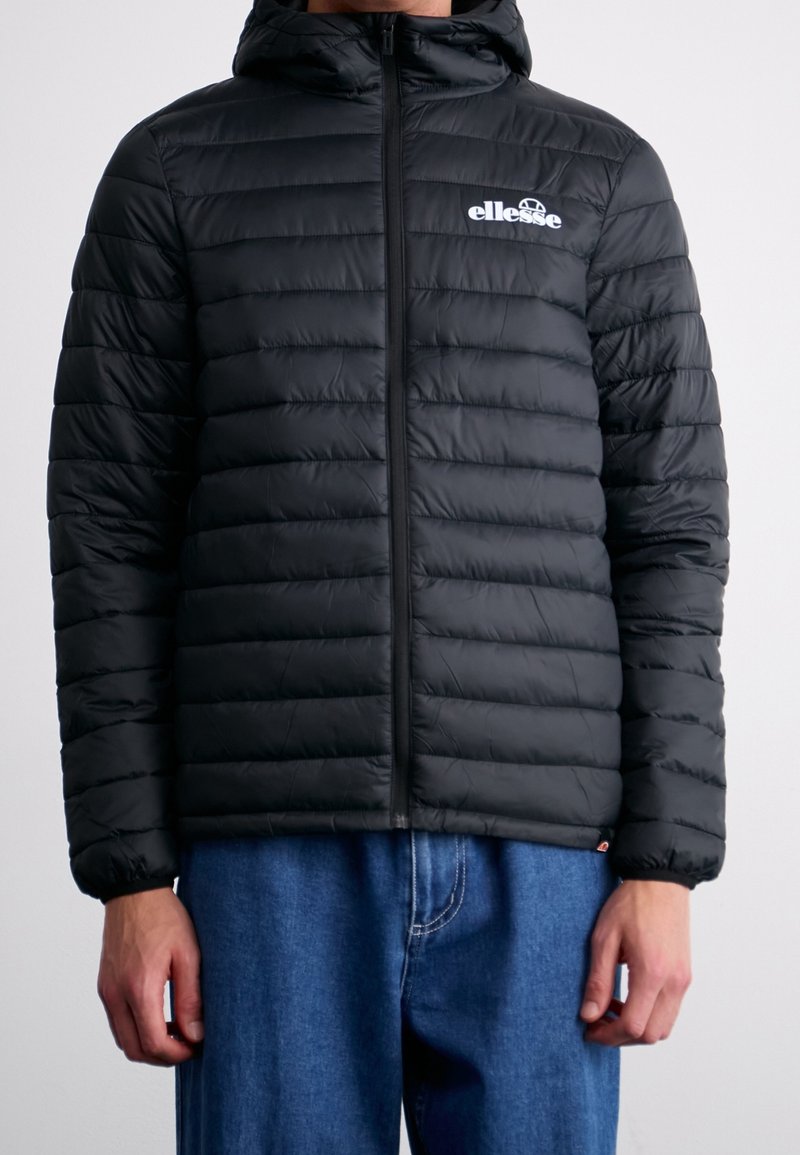 Czarna pikowana kurtka puchowa z pionowym wzorem przeszyć, kapturem i zamkiem błyskawicznym z przodu. Logo "Ellesse" w białym kolorze na lewym pasie piersiowym. Lekka tkanina.