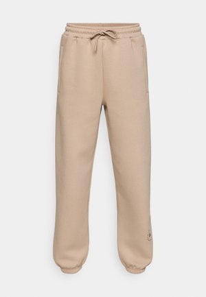 Beige sweatpants met een elastische tailleband en trekkoord, voorzien van zijzakken en geribbelde enkelboorden. Minimalistisch logo detail op de dij.